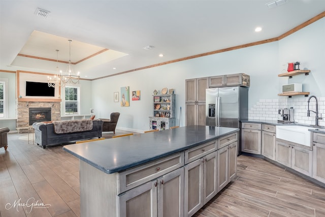 kitchen featuring sink, light hardwood / wood-style floors, a raised ceiling, and a kitchen island