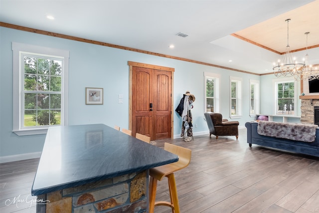 interior space featuring hardwood / wood-style floors, a fireplace, ornamental molding, a notable chandelier, and a tray ceiling