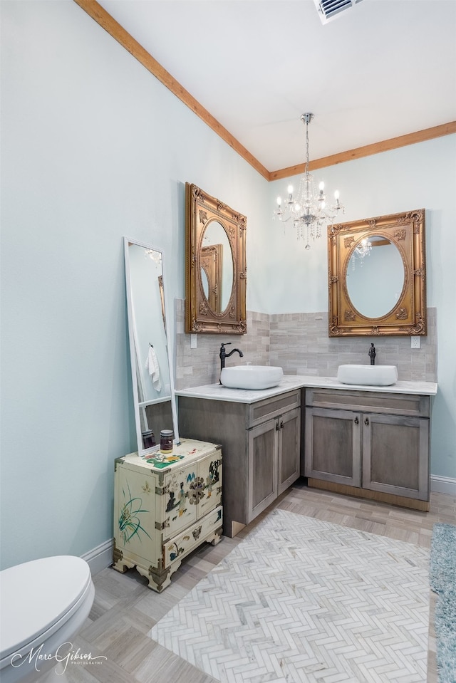 bathroom with toilet, a chandelier, ornamental molding, vanity, and backsplash