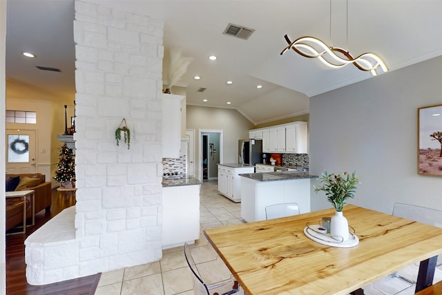 tiled dining area featuring ornamental molding and vaulted ceiling