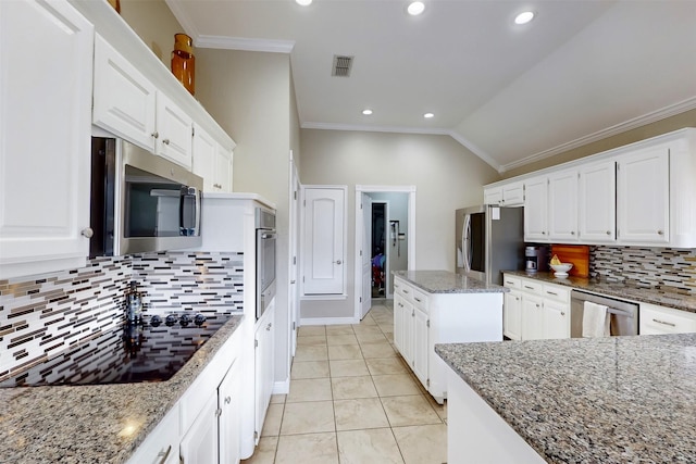 kitchen with appliances with stainless steel finishes, white cabinetry, vaulted ceiling, and dark stone counters