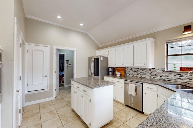 kitchen featuring white cabinets, dark stone counters, vaulted ceiling, a kitchen island, and appliances with stainless steel finishes