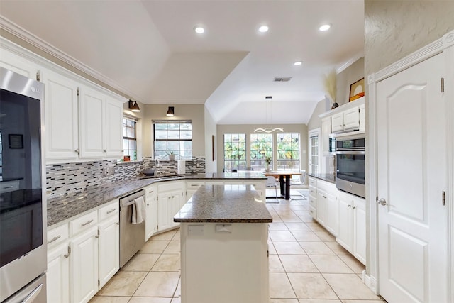 kitchen with white cabinetry, sink, vaulted ceiling, a kitchen island, and appliances with stainless steel finishes