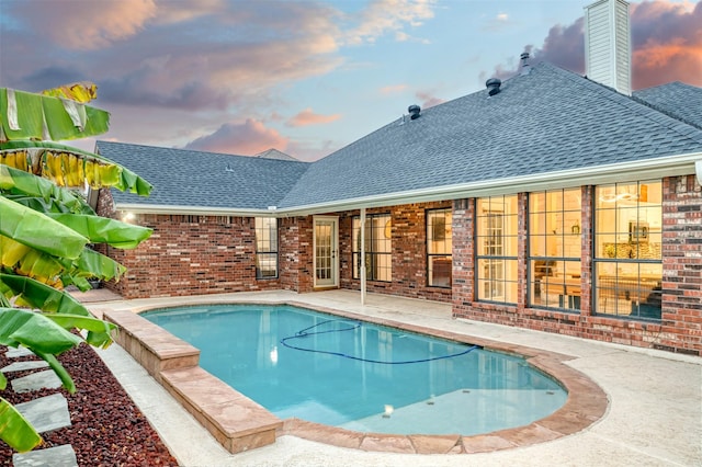 pool at dusk featuring a patio