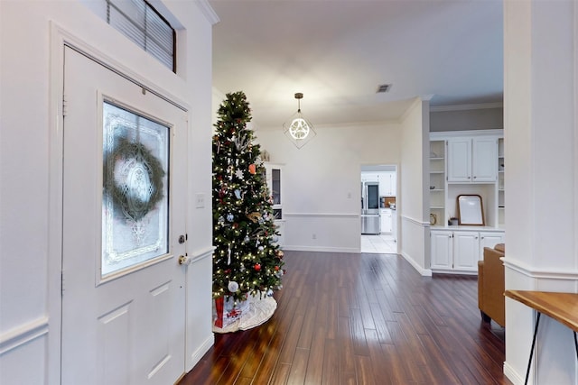 entryway featuring dark hardwood / wood-style floors, crown molding, and an inviting chandelier