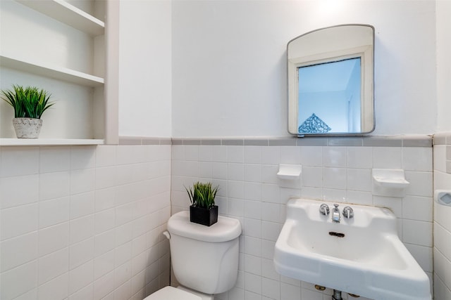 bathroom featuring toilet, sink, and tile walls