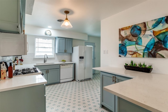 kitchen featuring pendant lighting, decorative backsplash, white appliances, and sink