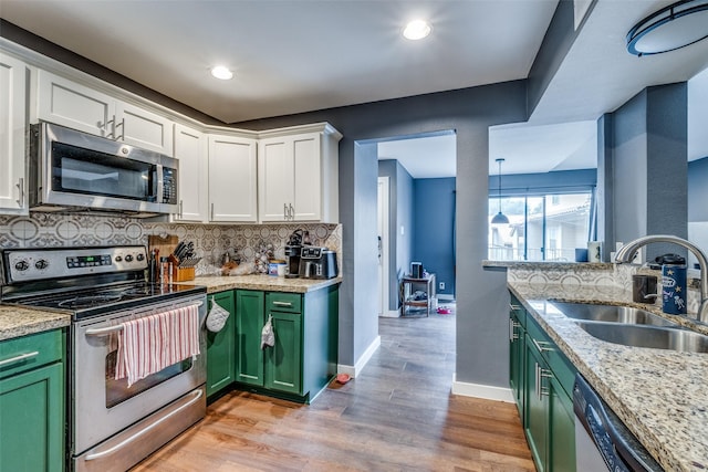 kitchen with green cabinetry, stainless steel appliances, sink, and white cabinets