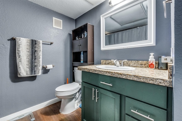 bathroom featuring vanity, hardwood / wood-style floors, a textured ceiling, and toilet