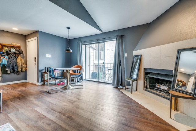 dining space featuring a tile fireplace, hardwood / wood-style flooring, and lofted ceiling