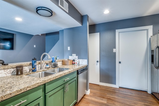 kitchen with sink, appliances with stainless steel finishes, green cabinetry, and light hardwood / wood-style flooring