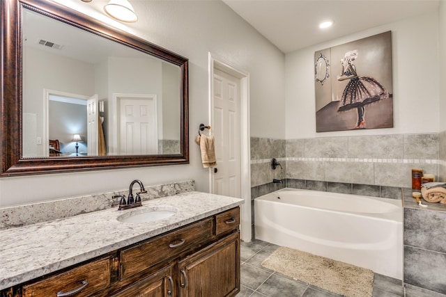 bathroom with tile patterned floors, a tub to relax in, and vanity