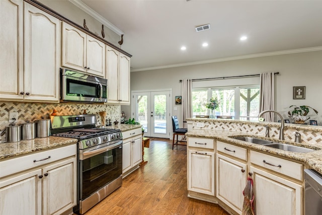 kitchen with tasteful backsplash, appliances with stainless steel finishes, sink, and light stone counters