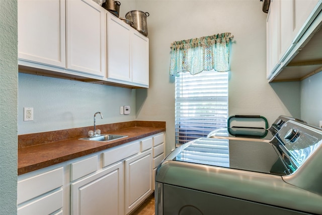 clothes washing area with sink, washer and clothes dryer, and cabinets