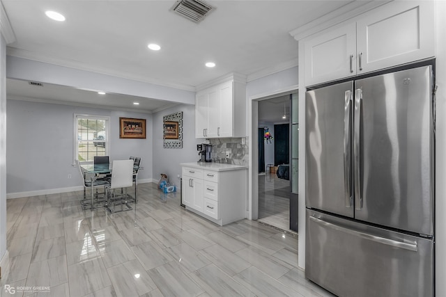 kitchen with stainless steel fridge, backsplash, white cabinetry, and crown molding