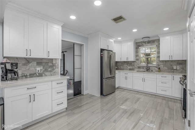 kitchen featuring light stone countertops, sink, crown molding, white cabinets, and appliances with stainless steel finishes