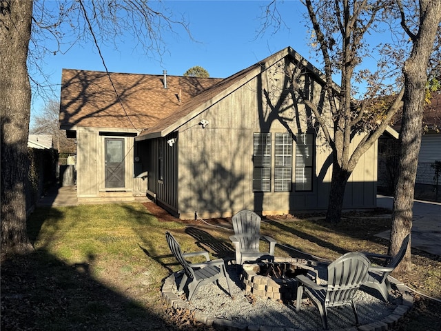 back of property with a lawn and an outdoor fire pit