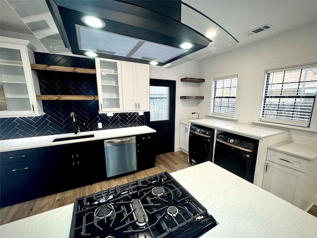 kitchen with stovetop, sink, white cabinetry, dishwasher, and washer / clothes dryer