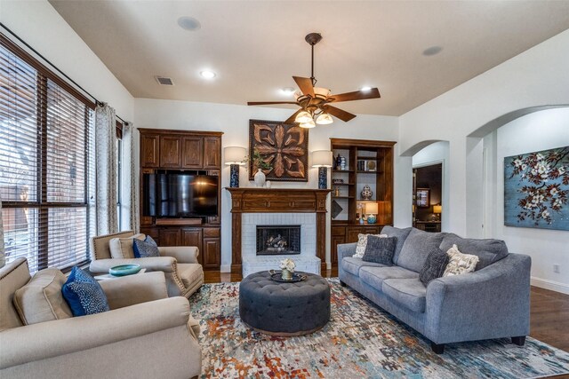 living room with ceiling fan, light wood-type flooring, and a brick fireplace