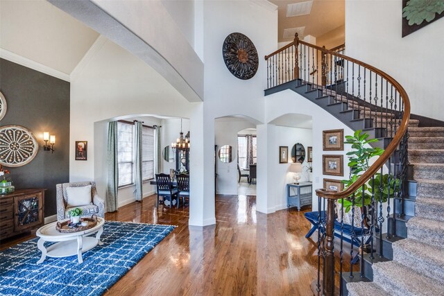 entrance foyer with a chandelier, french doors, a towering ceiling, and wood-type flooring