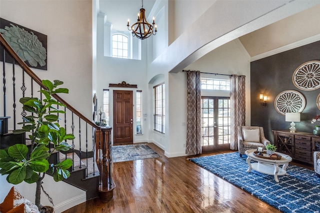 living room featuring french doors, crown molding, hardwood / wood-style flooring, high vaulted ceiling, and a chandelier