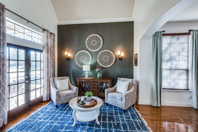 living room with a chandelier, crown molding, a towering ceiling, and wood-type flooring