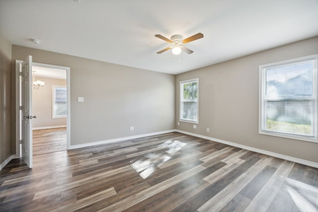 unfurnished room with ceiling fan with notable chandelier and dark wood-type flooring