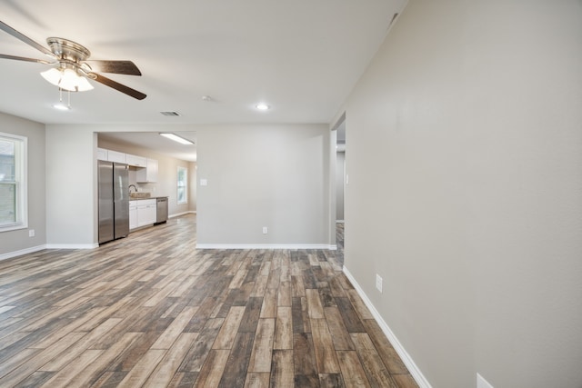 unfurnished living room with hardwood / wood-style flooring, ceiling fan, and sink