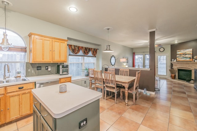 kitchen featuring hanging light fixtures, a kitchen island, sink, and a wealth of natural light