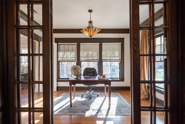 home office with wood-type flooring and ornamental molding