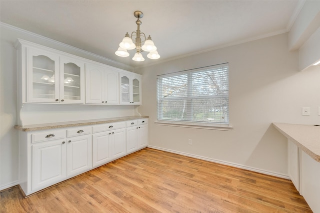 unfurnished dining area with crown molding, light hardwood / wood-style floors, and an inviting chandelier