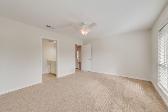 unfurnished bedroom with ensuite bathroom, ceiling fan, and light colored carpet