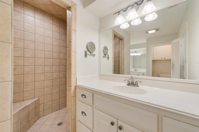 bathroom featuring tiled shower, tile patterned floors, vanity, and toilet