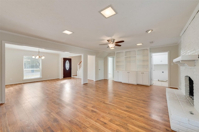 unfurnished living room with ceiling fan with notable chandelier, light wood-type flooring, a brick fireplace, and ornamental molding