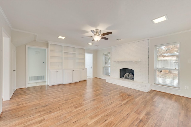 unfurnished living room with ceiling fan, light wood-type flooring, crown molding, and a brick fireplace