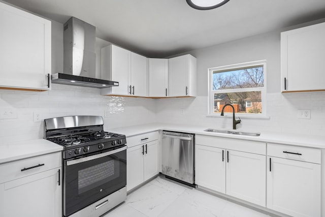 kitchen featuring backsplash, wall chimney range hood, sink, appliances with stainless steel finishes, and white cabinetry