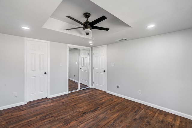 unfurnished bedroom with ceiling fan and dark wood-type flooring