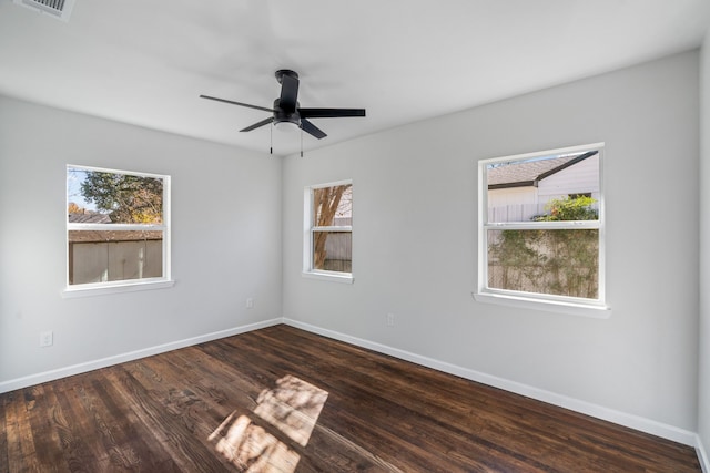 spare room featuring a wealth of natural light, ceiling fan, and dark wood-type flooring