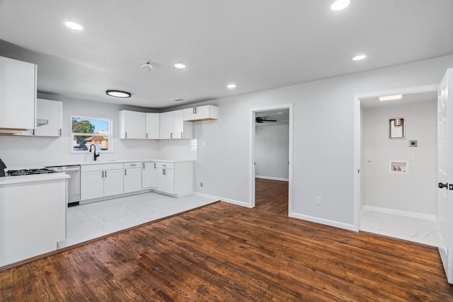 kitchen with tasteful backsplash, sink, dishwasher, white cabinets, and light hardwood / wood-style floors