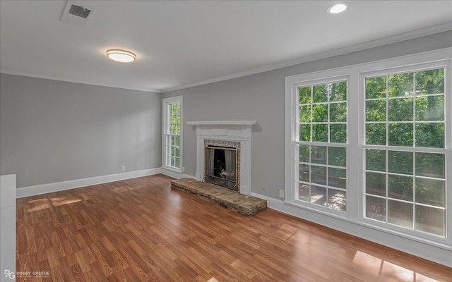 unfurnished living room with a fireplace, wood-type flooring, plenty of natural light, and ornamental molding