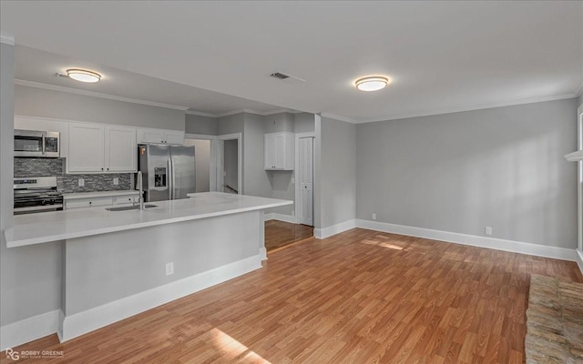 kitchen featuring light hardwood / wood-style floors, white cabinetry, ornamental molding, and appliances with stainless steel finishes