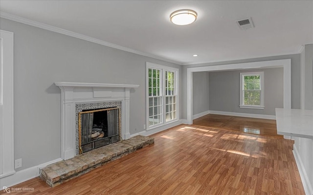 unfurnished living room featuring hardwood / wood-style floors, ornamental molding, and a healthy amount of sunlight