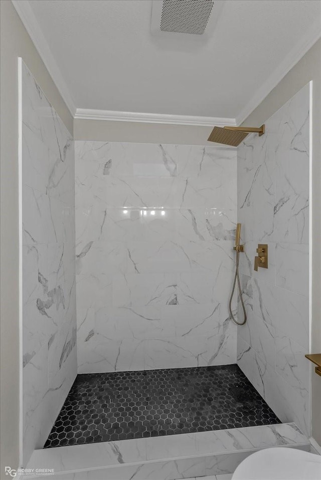 bathroom with toilet, a tile shower, and ornamental molding