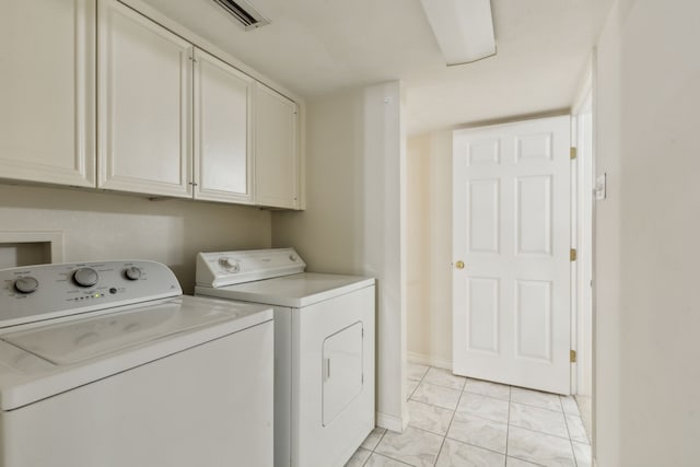 clothes washing area with cabinets and separate washer and dryer