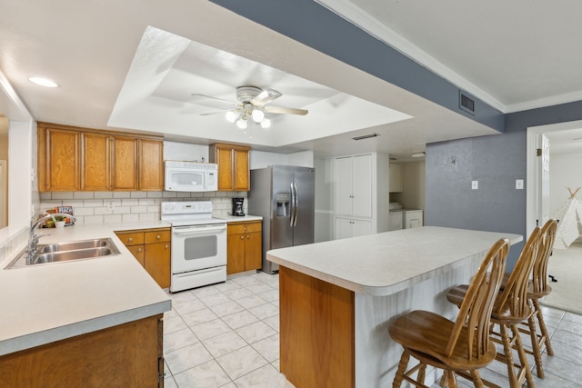 kitchen with white appliances, backsplash, sink, ceiling fan, and washing machine and dryer