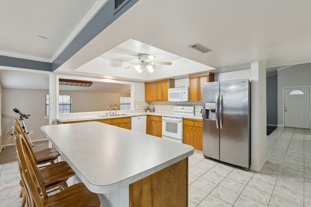 kitchen with ceiling fan, sink, backsplash, kitchen peninsula, and white appliances