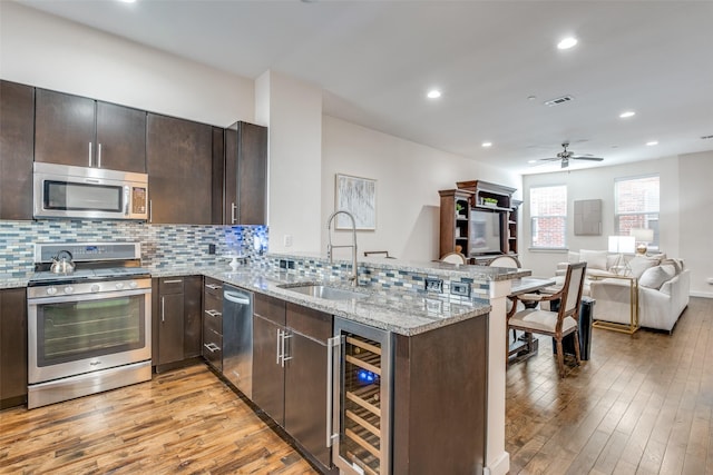 kitchen featuring kitchen peninsula, sink, beverage cooler, and stainless steel appliances