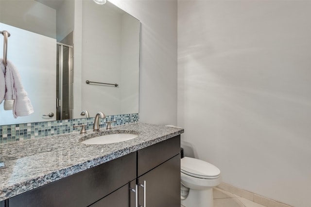 bathroom featuring tasteful backsplash, tile patterned floors, toilet, vanity, and a shower with shower door