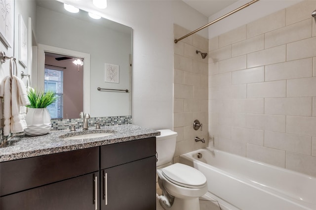 full bathroom featuring vanity, tiled shower / bath combo, toilet, and ceiling fan