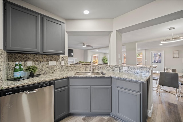 kitchen featuring sink, light stone counters, gray cabinets, dishwasher, and kitchen peninsula